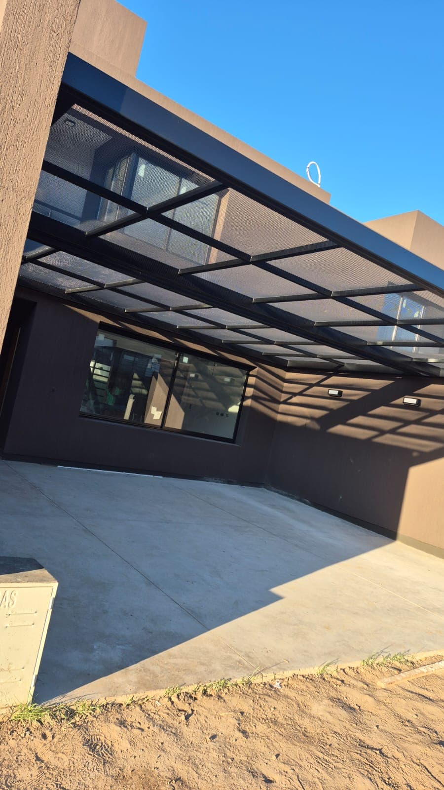 Estructura metálica con techo de chapa perforada sobre la galería de una casa